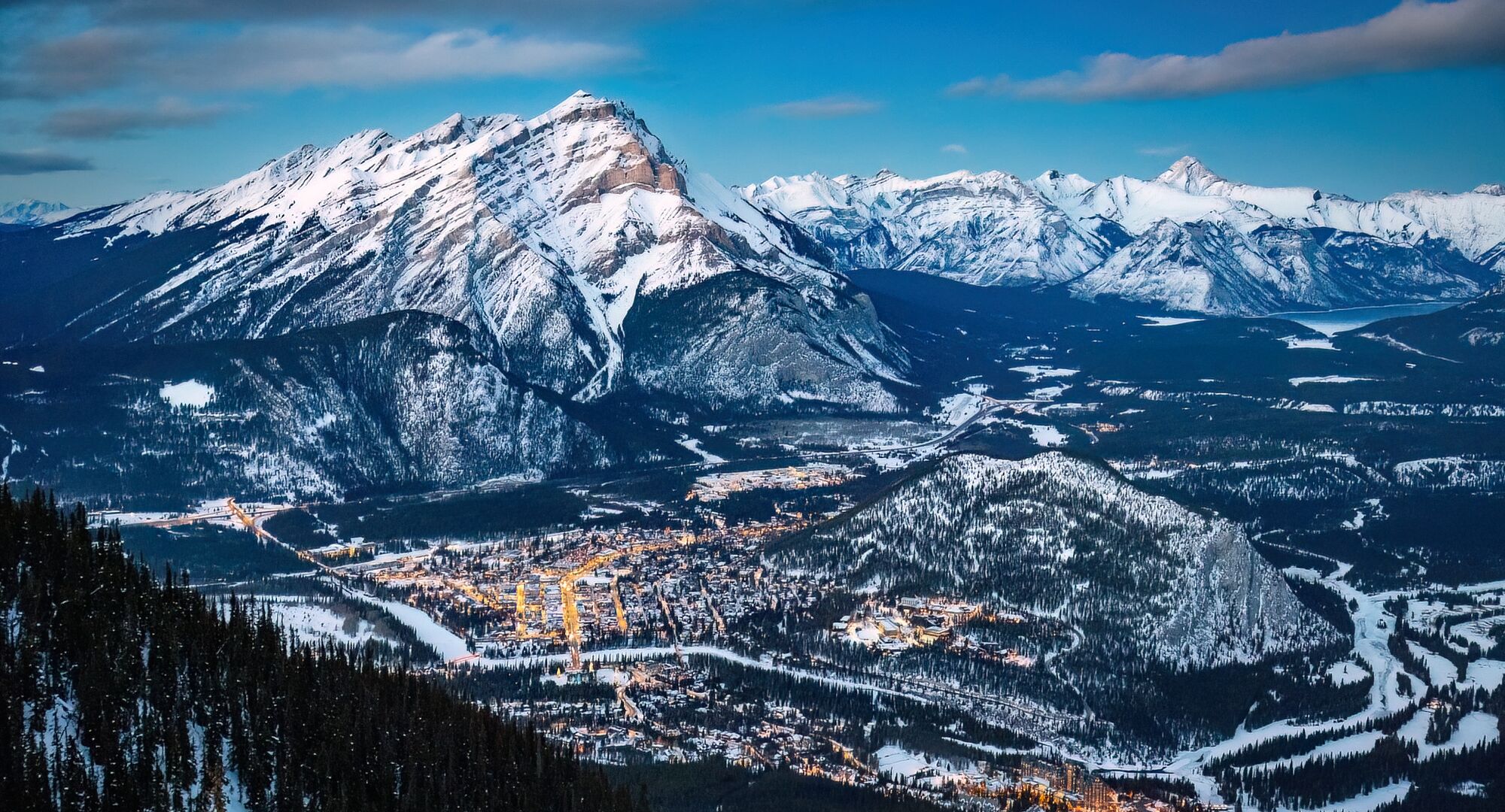 The Banff Townsite light up at night as seen from the BAnff Gondola on top of Sulphur Mountain with Cascade Mountain looming in the background in Banff NAtional PArk.